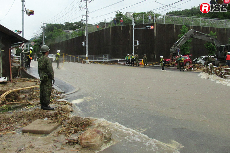 濁流が流れる県道34号線の天神交差点。水難装備を着装した警視庁の救助隊員が親綱を設定し往来の補助を行っていた。