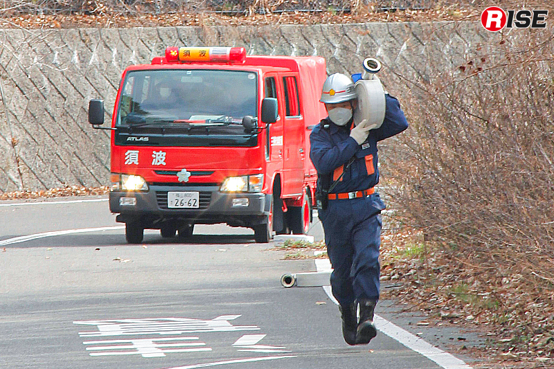 平均勾配8.9％の坂道を肩にホースを担いで走る消防団員。